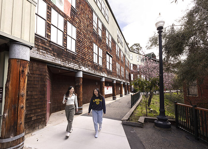 Two students walk along a pathway next to one of Foothill’s wood-shingled buildings.