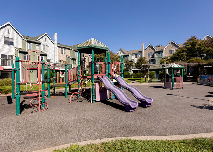 A children's playground is shown surrounded by a row of University Village apartment buildings.